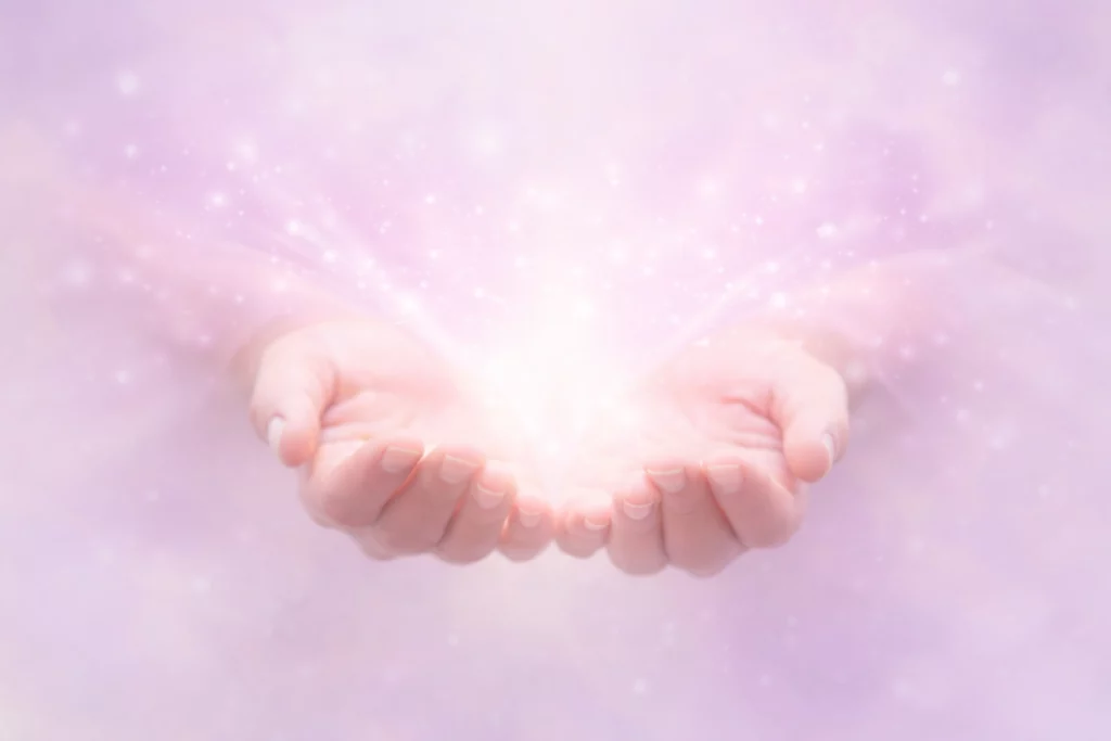 Mains lumineuses symbolisant l’énergie et l’accompagnement spirituel pour une prise de contact avec une thérapeute en soins énergétiques
